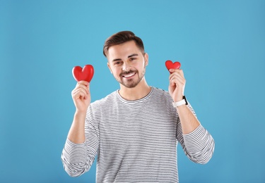Photo of Man holding decorative hearts on color background