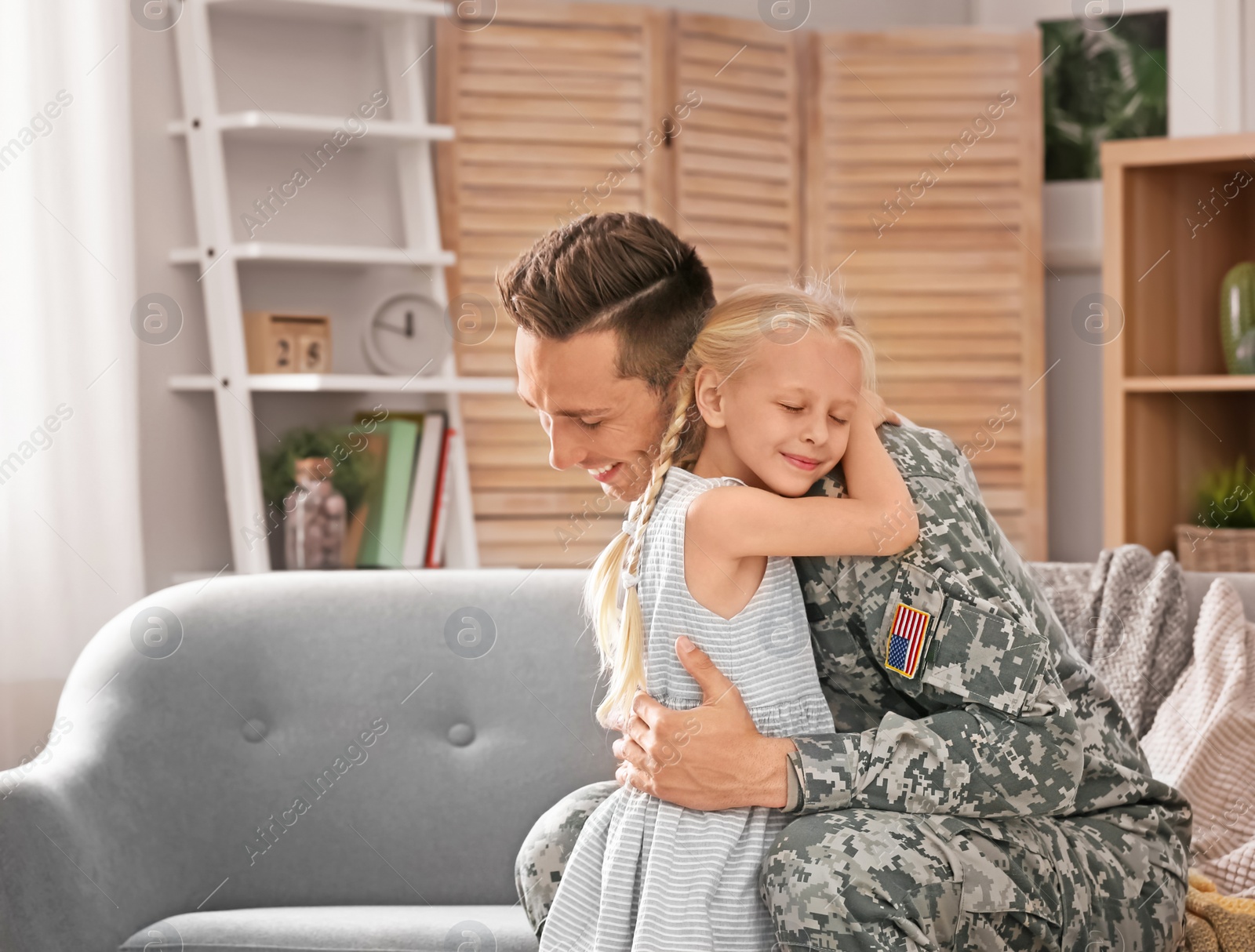Photo of Young man in military uniform with his little daughter at home