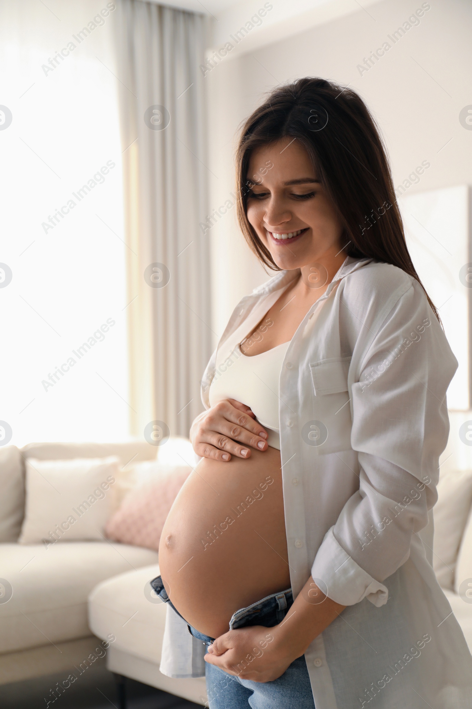 Photo of Pregnant young woman touching belly at home