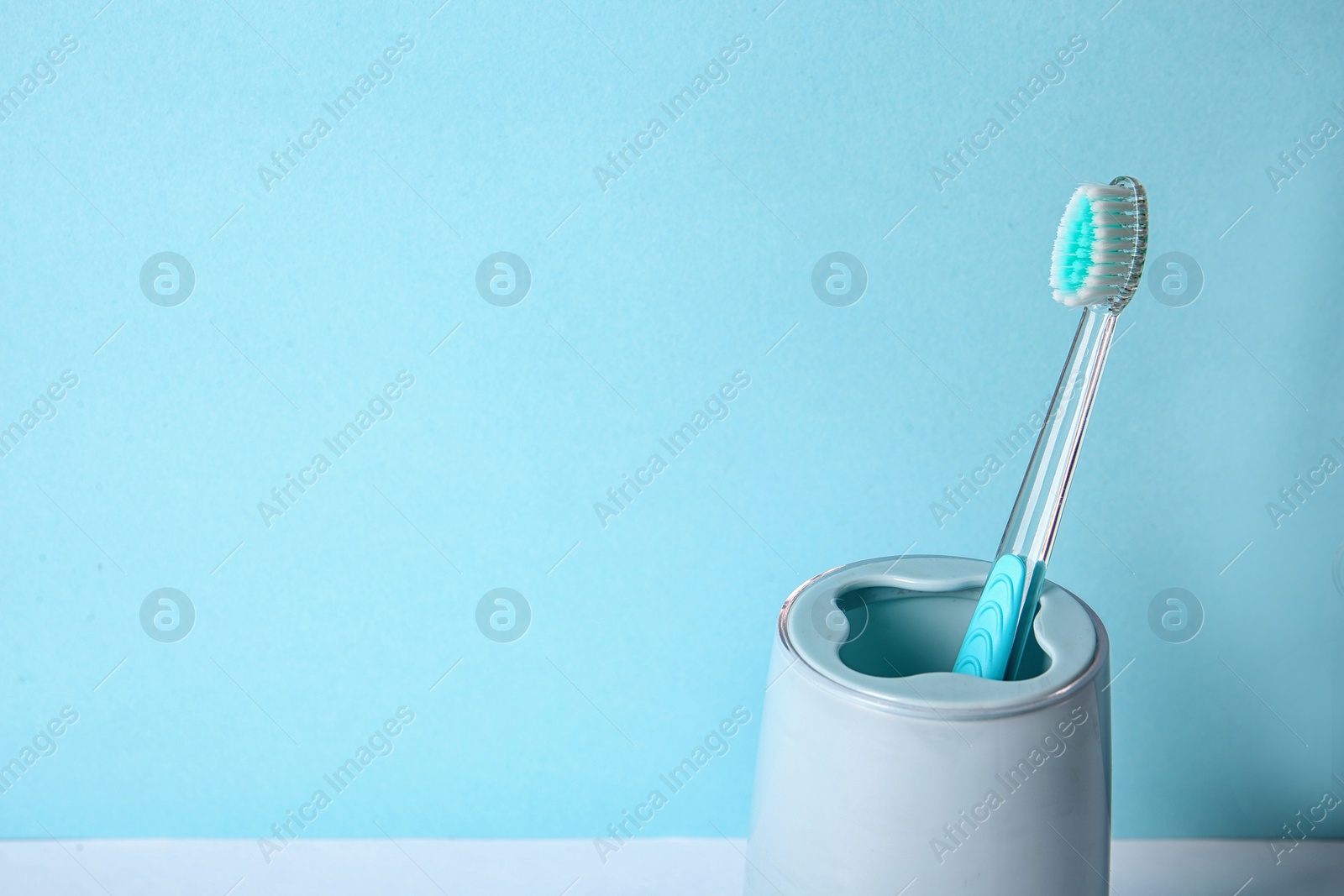 Photo of Cup with toothbrush against color background