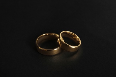 Photo of Beautiful gold wedding rings on black background