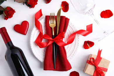 Photo of Beautiful place setting for romantic dinner on white wooden table, flat lay. Valentine's day celebration