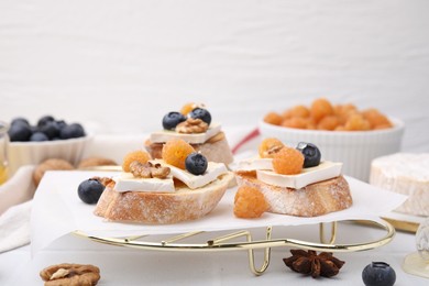 Photo of Tasty sandwiches with brie cheese, fresh berries and walnuts on white table. Space for text