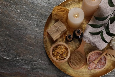 Photo of Spa composition. Brushes, bottles and sea salt on grey textured table, top view. Space for text