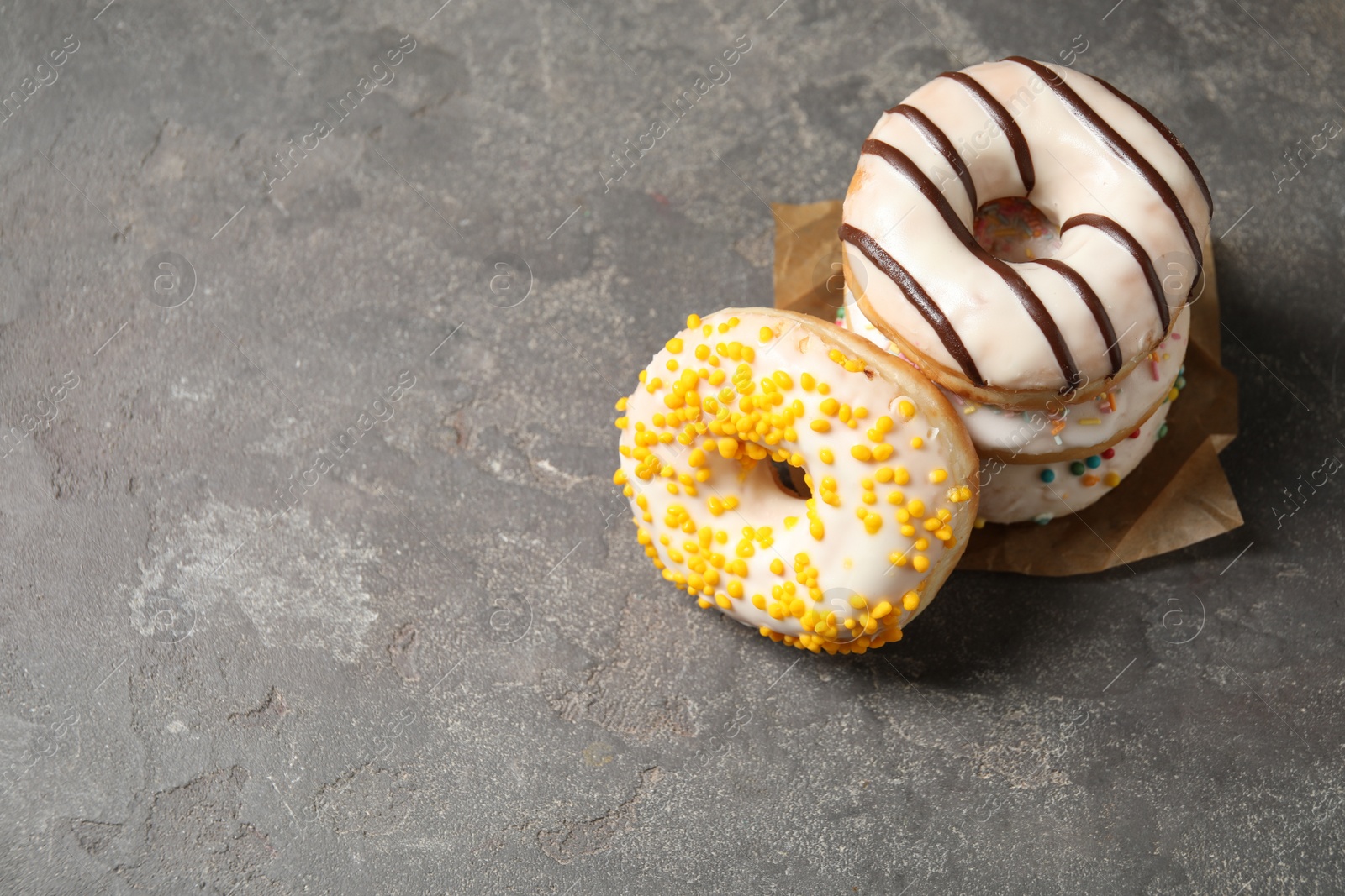 Photo of Delicious glazed donuts on grey table. Space for text