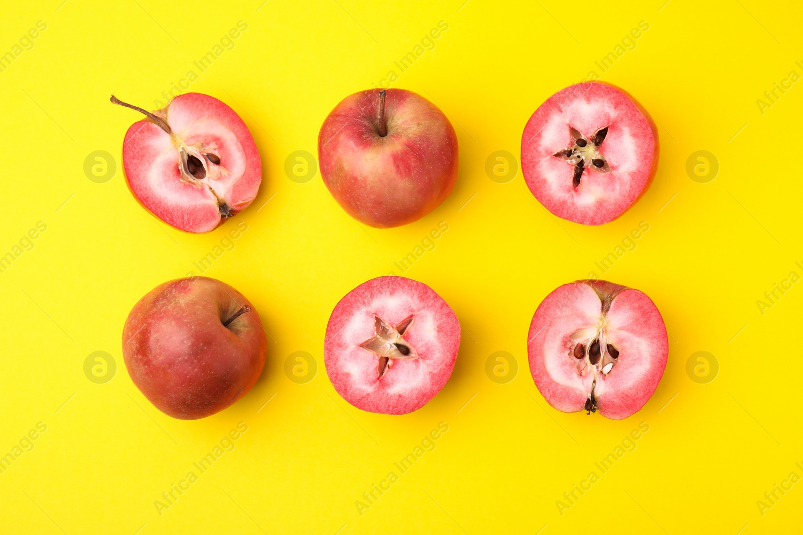 Photo of Tasty apples with red pulp on yellow background, flat lay