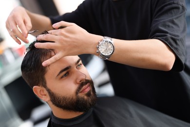 Professional hairdresser working with client in barbershop