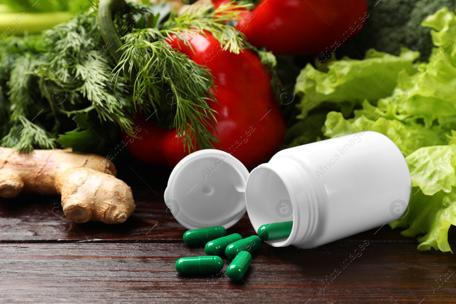 Photo of Dietary supplements. Overturned bottle, pills and food products on wooden table