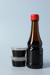 Photo of Bottle and bowls with soy sauce on light grey background