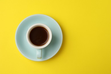 Tasty coffee in cup on yellow background, top view. Space for text