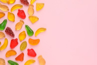 Tasty jelly candies in shape of different fruits on pink background, flat lay. Space for text