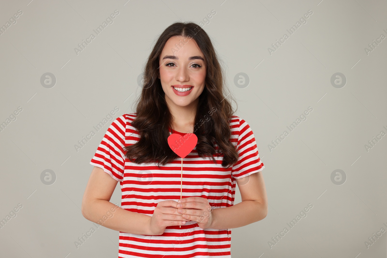 Photo of Beautiful young woman with paper heart on grey background