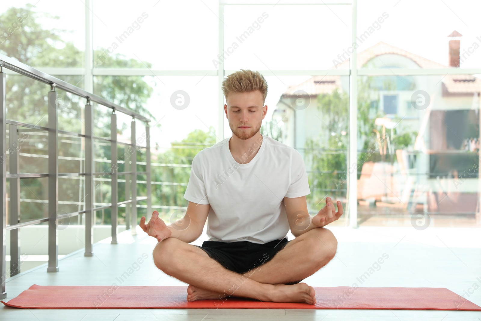 Photo of Handsome young man practicing zen yoga indoors