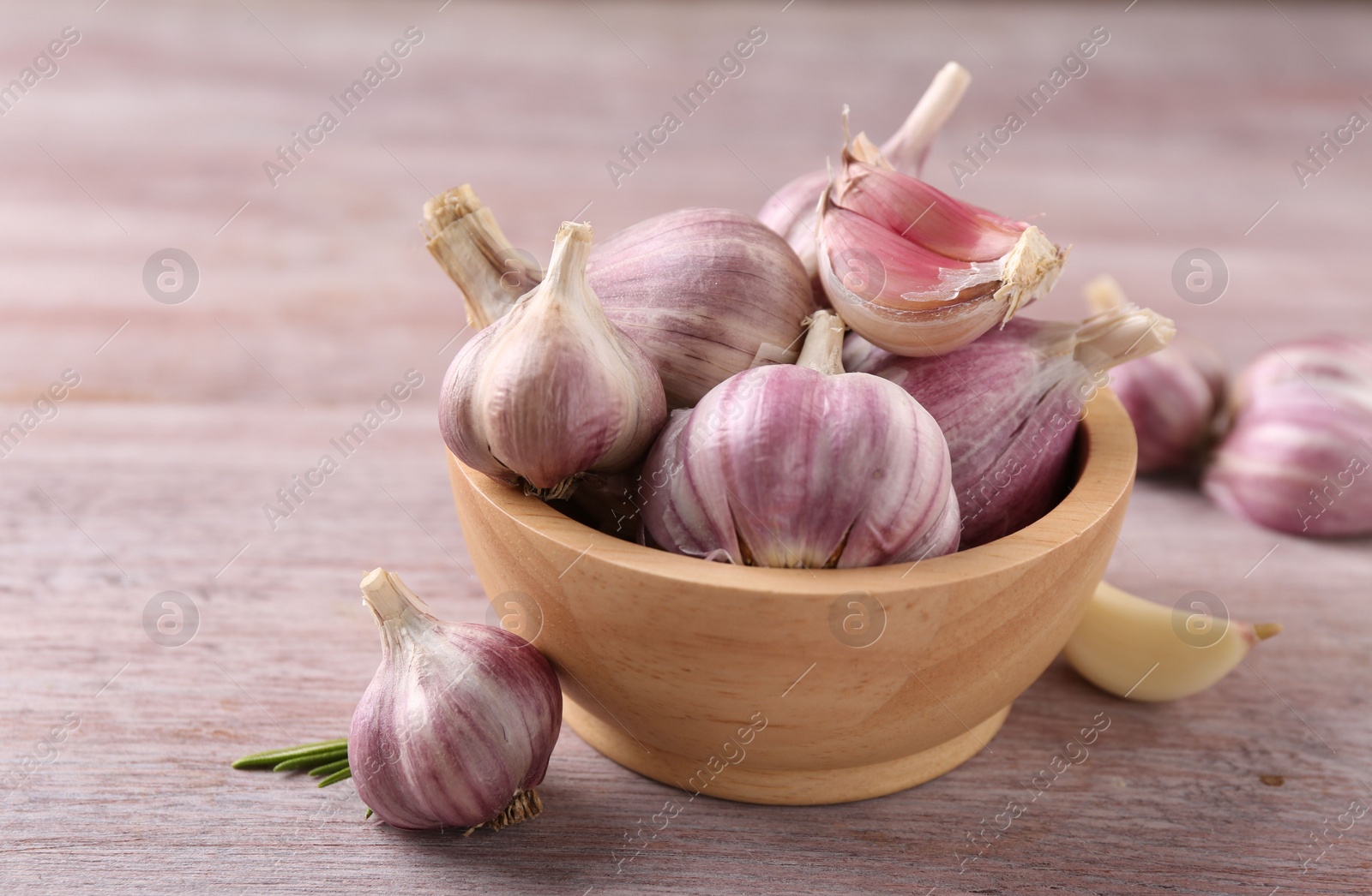 Photo of Bowl with fresh garlic on wooden table, closeup