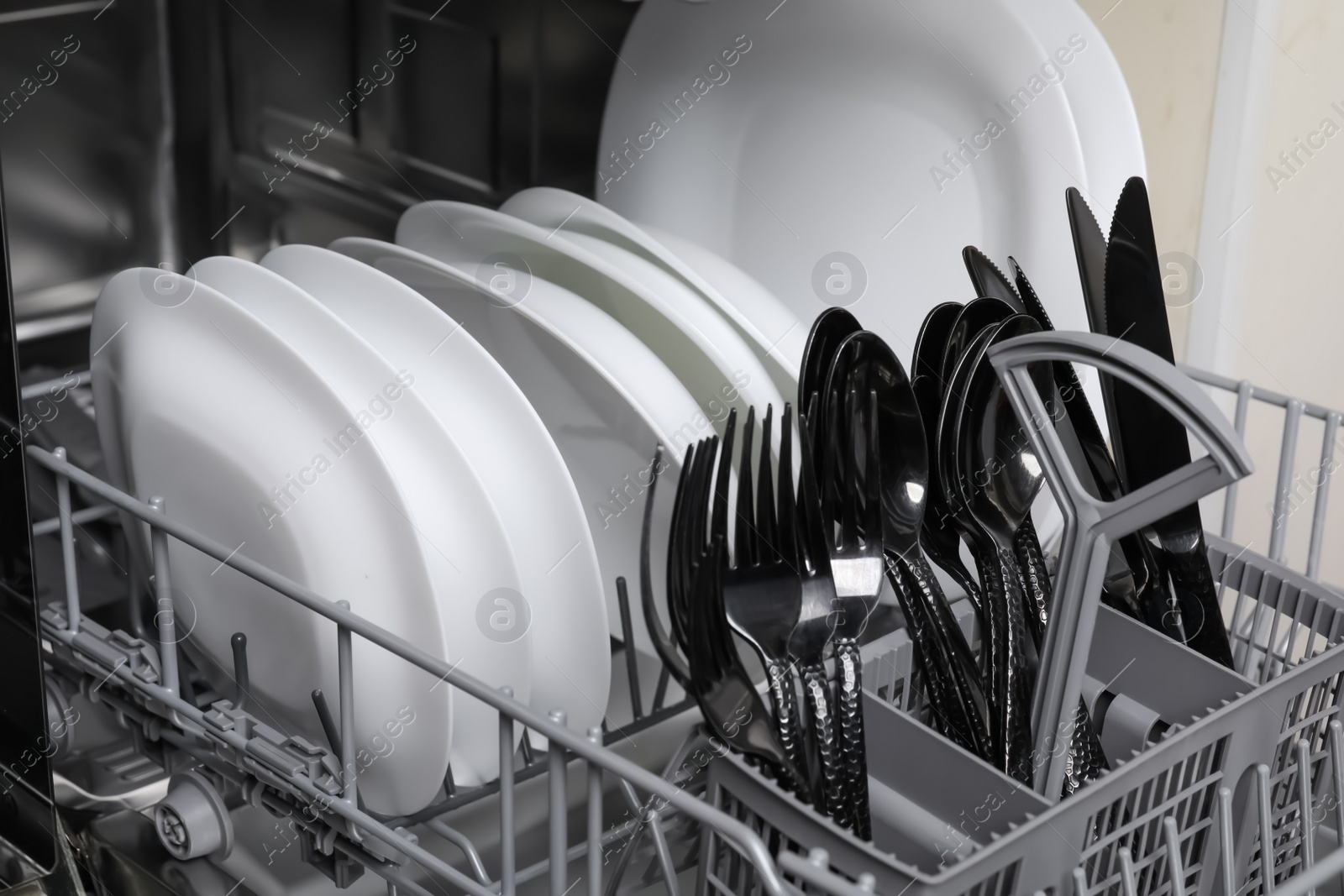 Photo of Open modern dishwasher with clean tableware, closeup