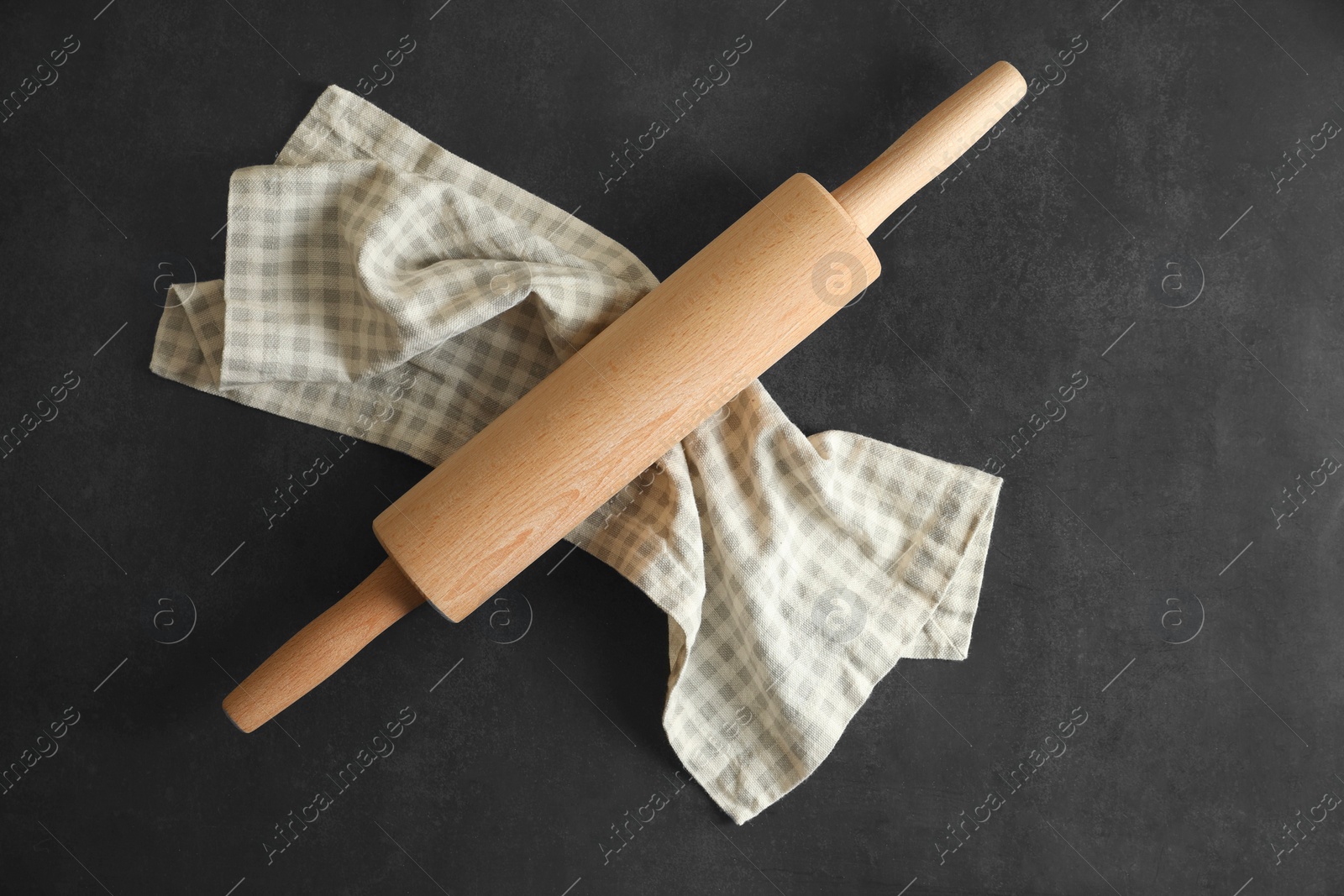 Photo of Rolling pin and kitchen towel on black table, top view