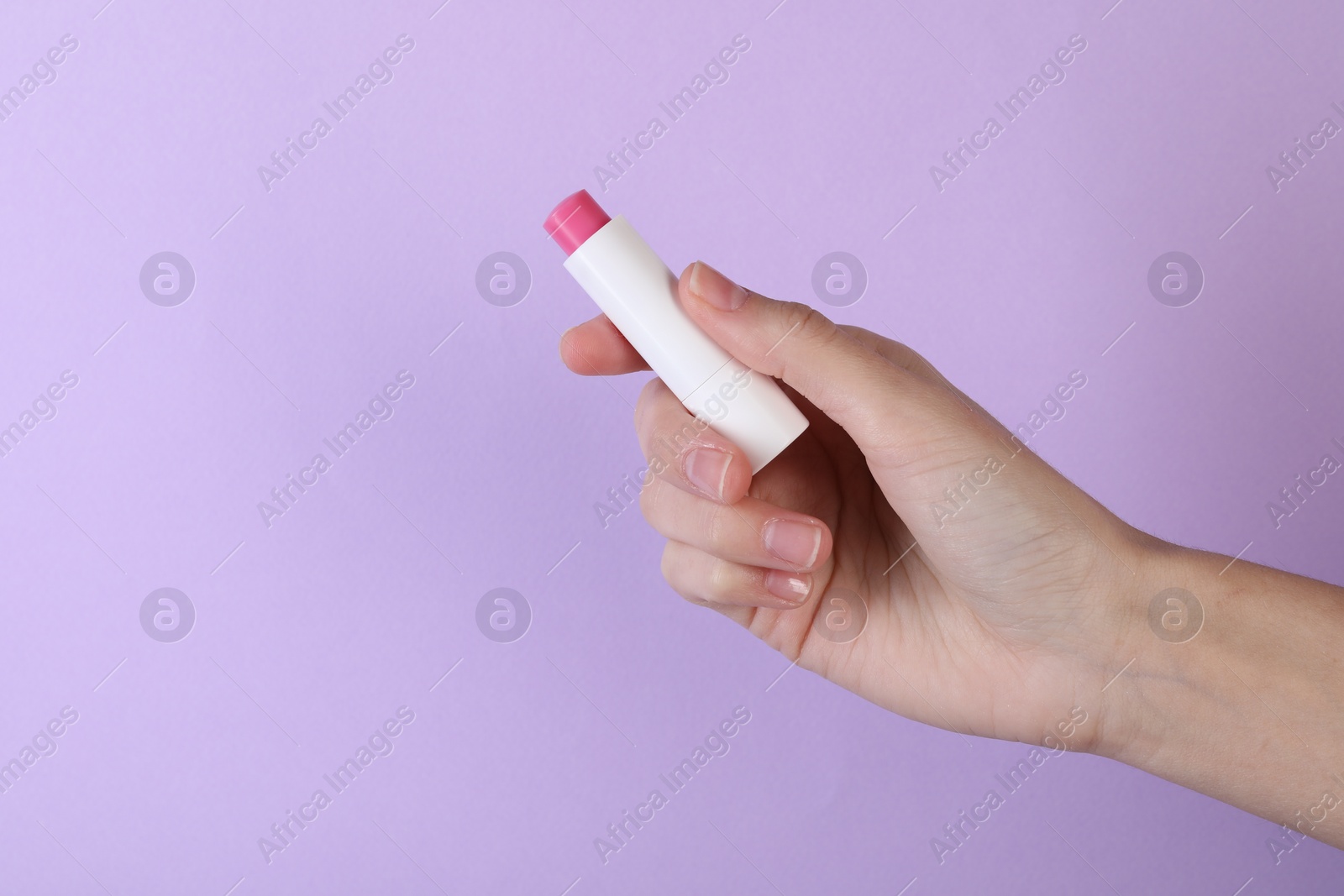 Photo of Woman with lip balm on violet background, closeup