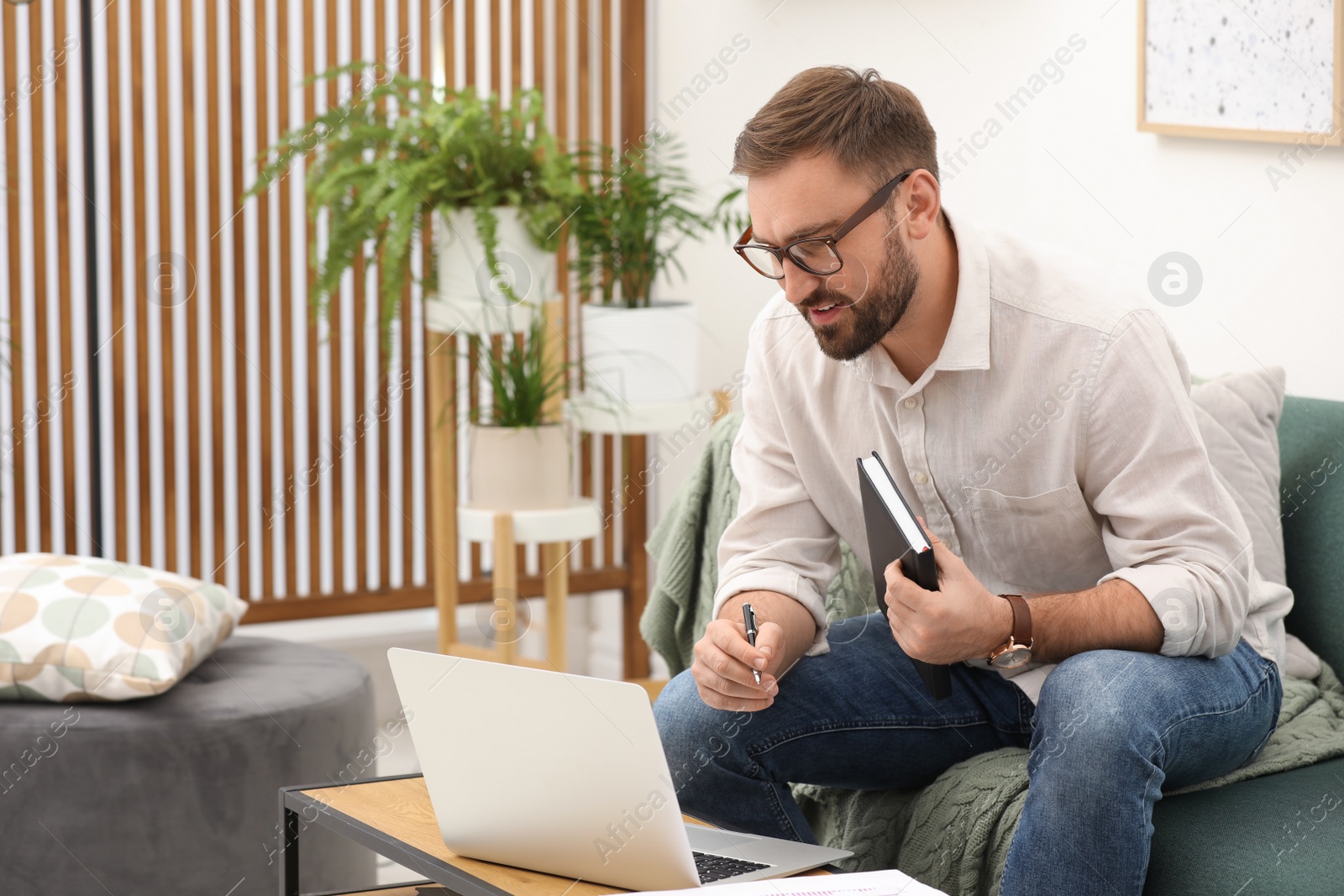 Photo of Young man working with notebook and laptop at home