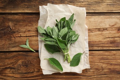 Photo of Bunch of fresh sage leaves on wooden table, flat lay