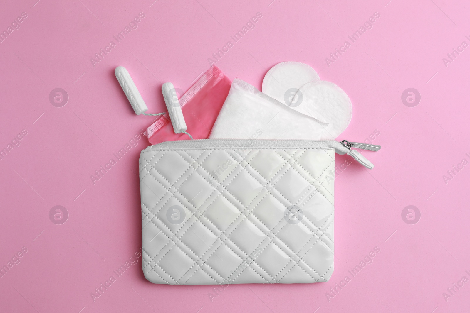 Photo of Bag with menstrual pads, tampons and pantyliners on pink background, flat lay