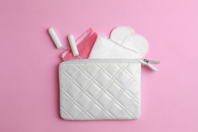 Photo of Bag with menstrual pads, tampons and pantyliners on pink background, flat lay