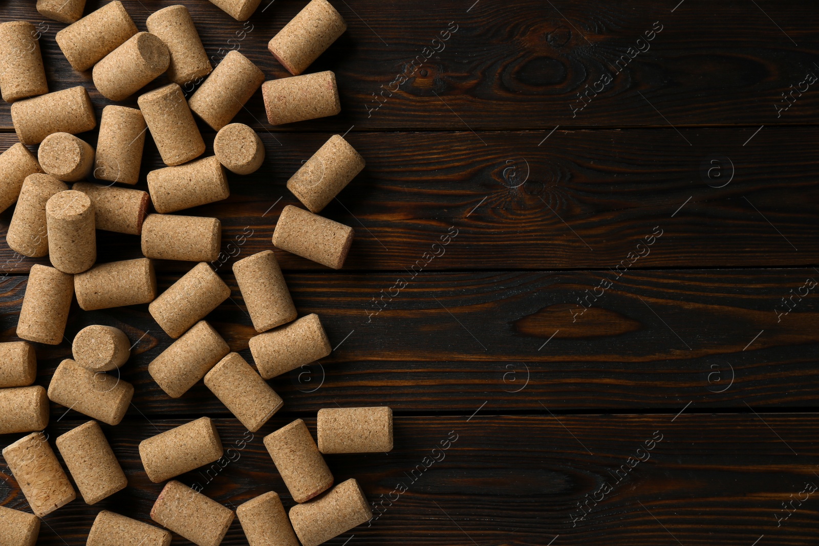 Photo of Many corks of wine bottles on wooden table, flat lay. Space for text