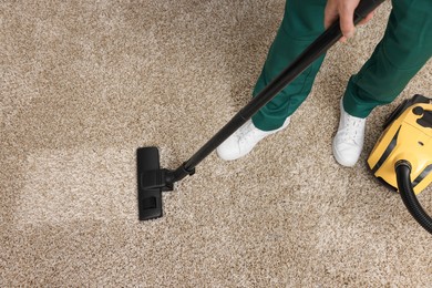 Photo of Dry cleaner's employee hoovering carpet with vacuum cleaner, above view