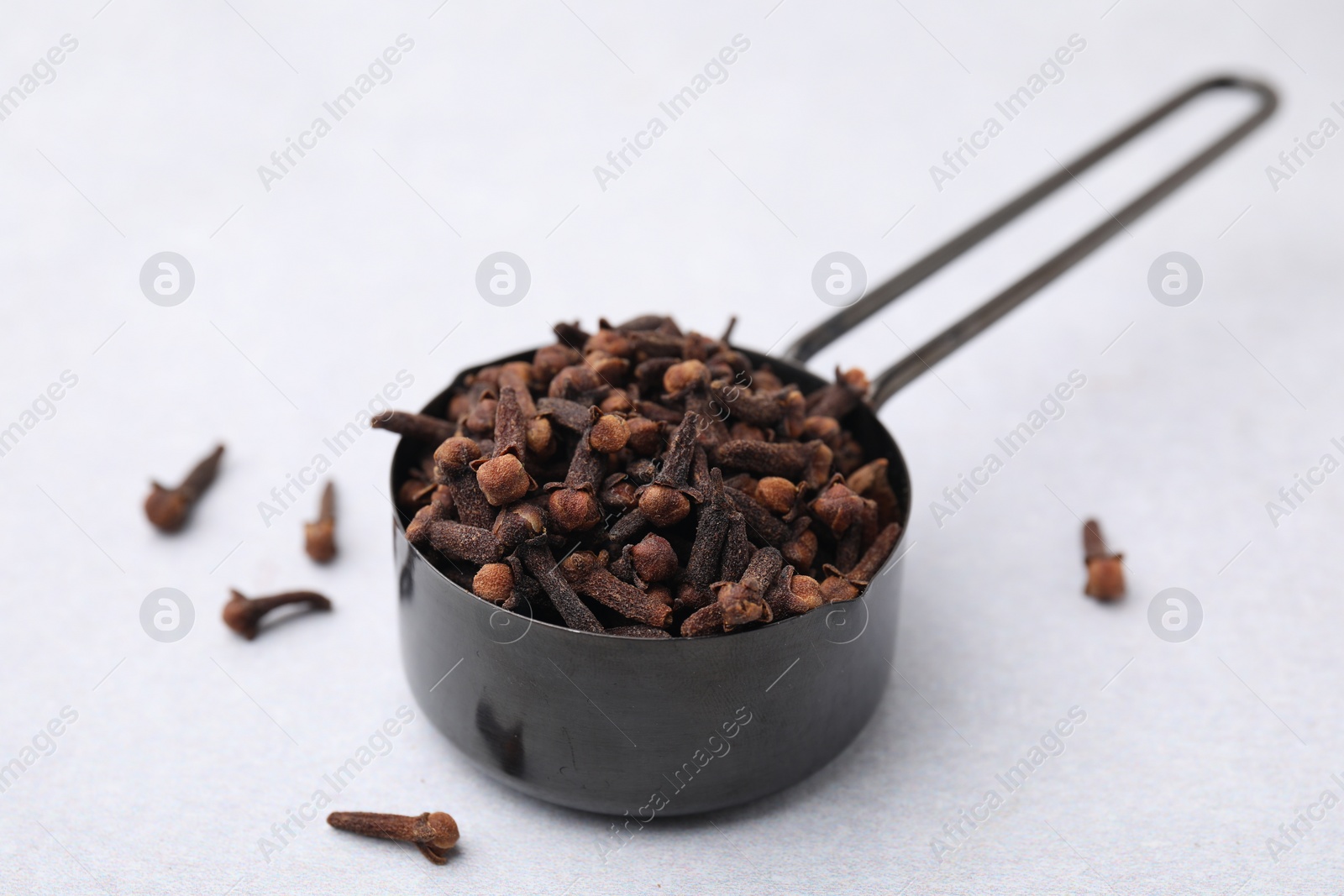 Photo of Aromatic cloves in scoop on light table, closeup