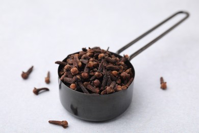 Photo of Aromatic cloves in scoop on light table, closeup