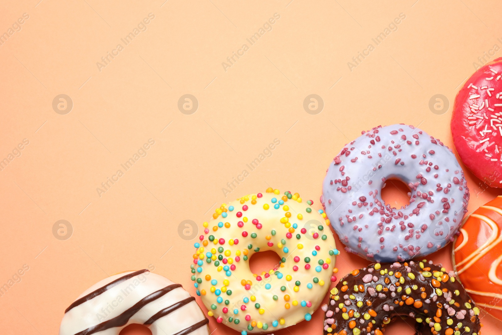 Photo of Delicious glazed donuts on orange background, flat lay. Space for text