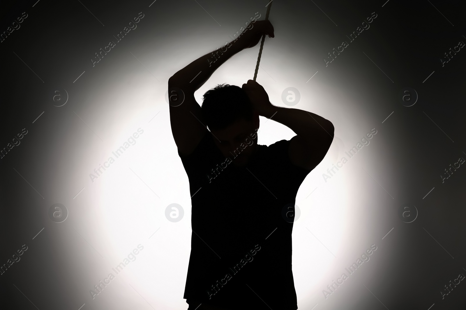 Photo of Silhouette of man with rope noose on neck against light background
