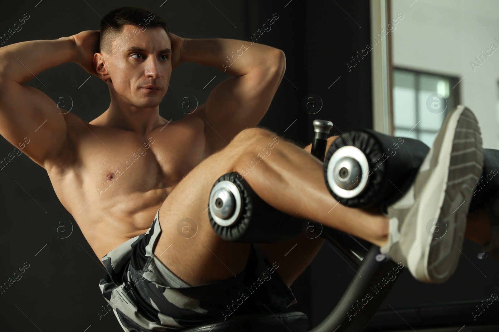 Photo of Man working out on adjustable sit up bench in modern gym