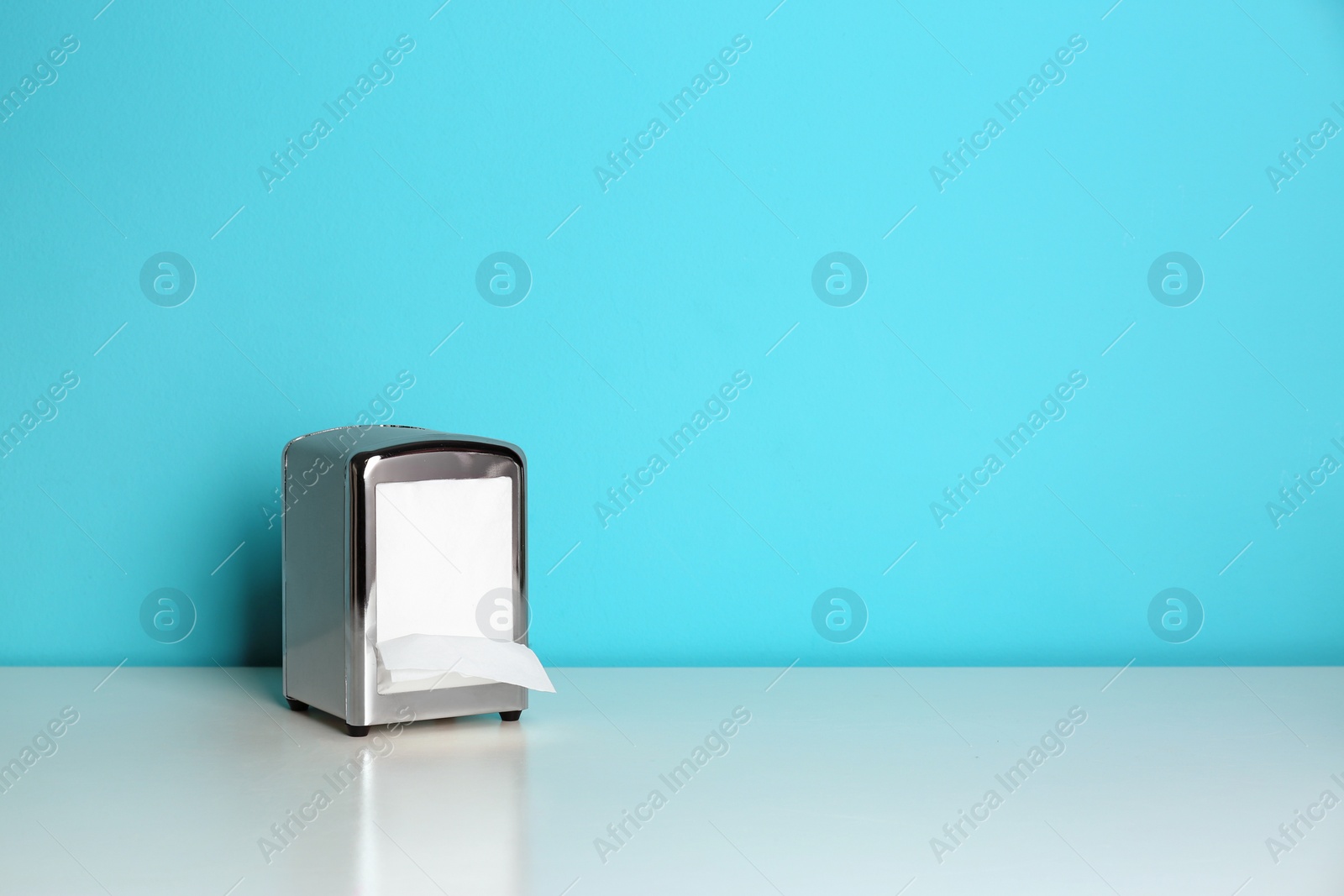 Photo of Napkin holder with paper serviettes on table. Space for text