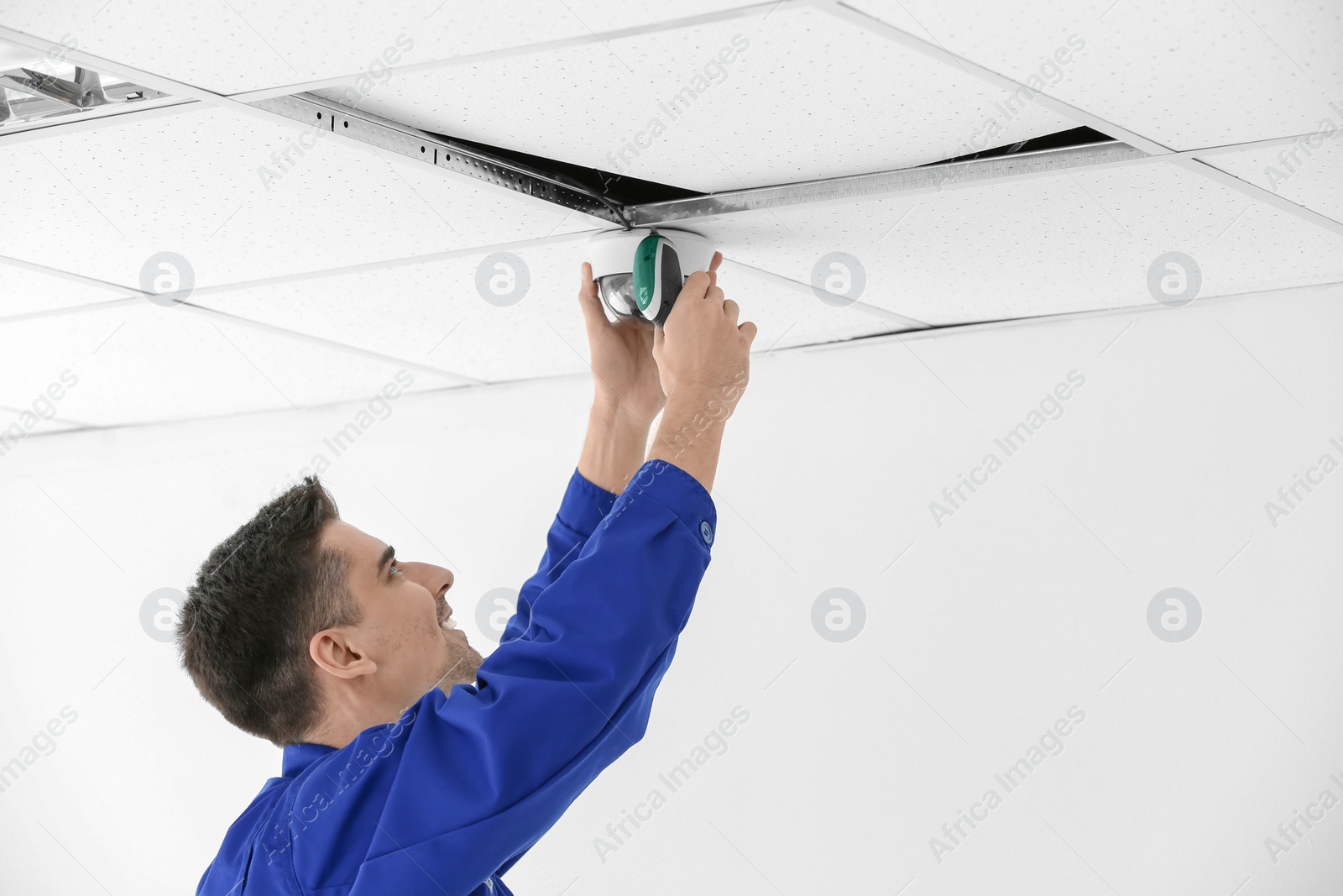 Photo of Technician installing CCTV camera on ceiling indoors