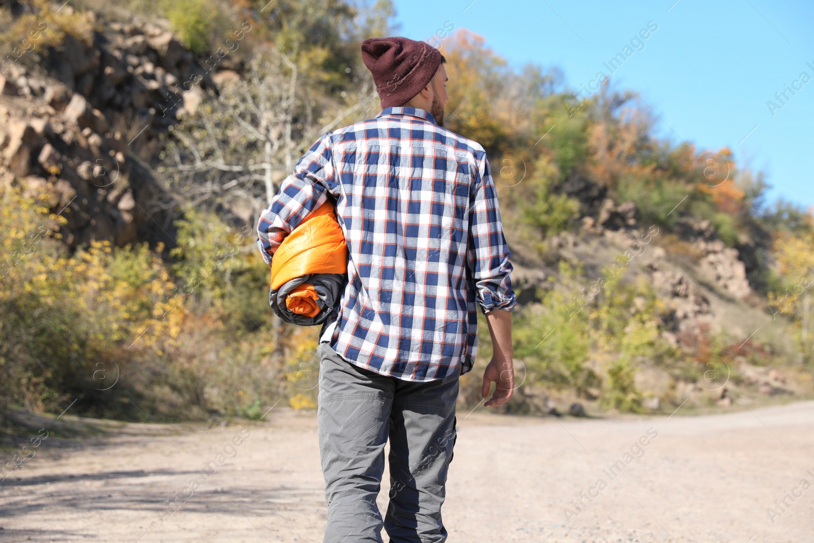 Photo of Young male camper with sleeping bag in wilderness