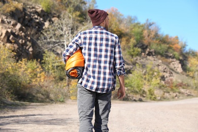 Photo of Young male camper with sleeping bag in wilderness