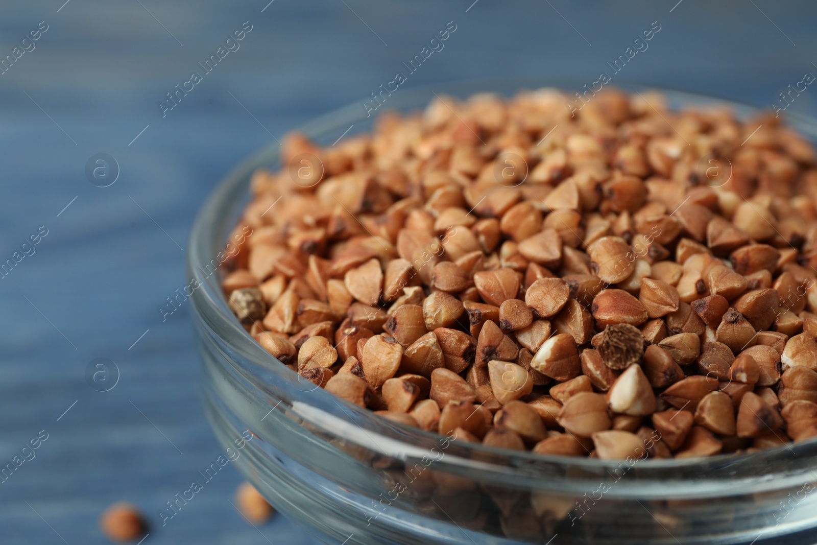 Photo of Uncooked buckwheat grains in glass bowl, closeup