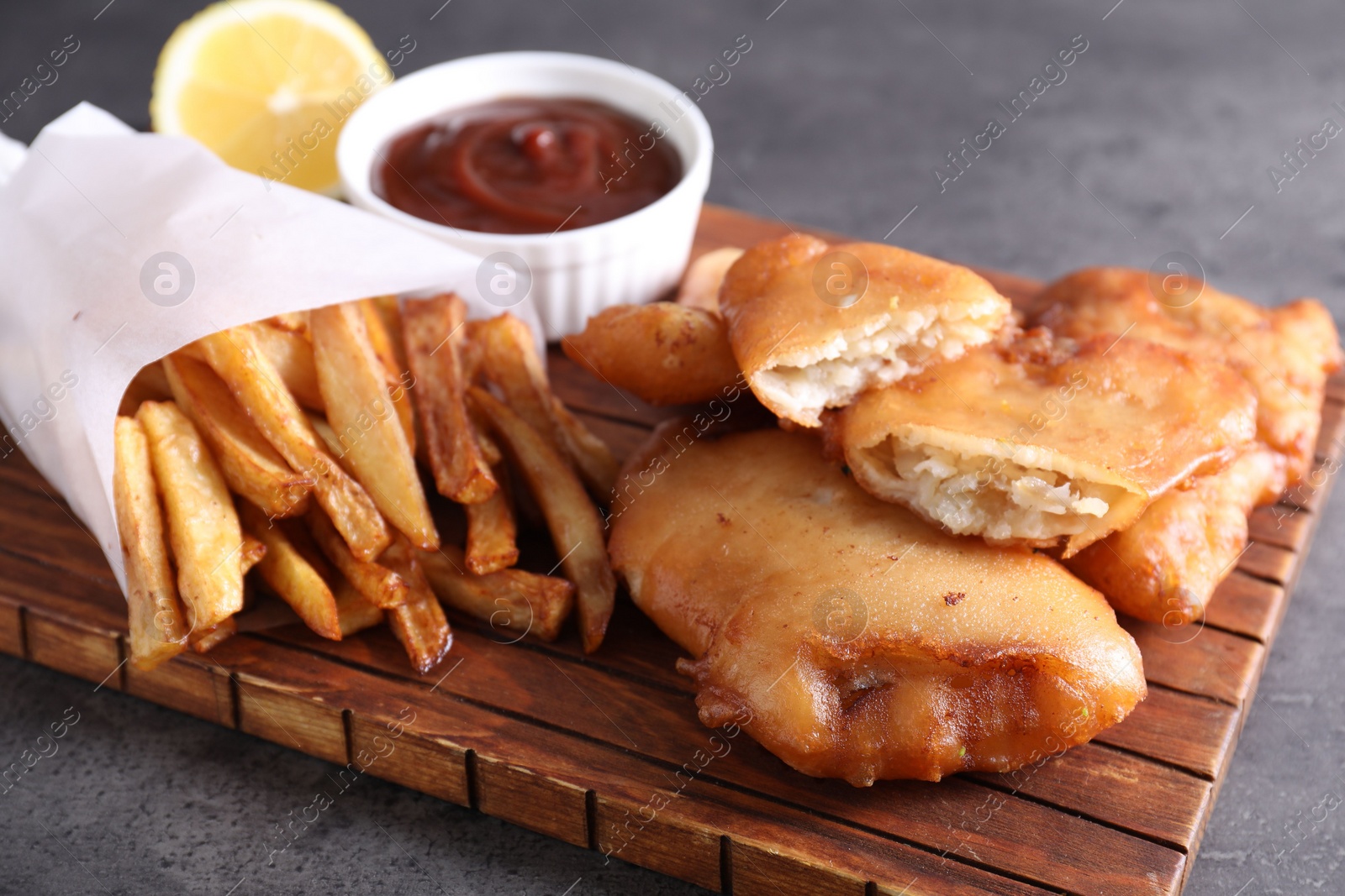 Photo of Tasty fish, chips and sauce on grey table, closeup