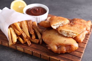 Tasty fish, chips and sauce on grey table, closeup