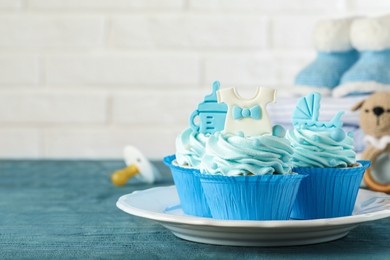 Photo of Beautifully decorated baby shower cupcakes with cream and boy toppers on grey wooden table. Space for text