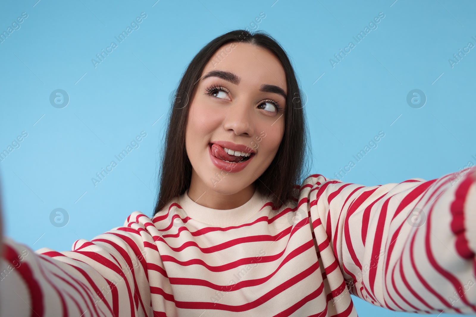 Photo of Young woman taking selfie on light blue background