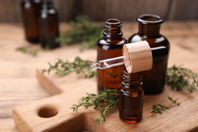 Photo of Thyme essential oil and fresh plant on wooden table