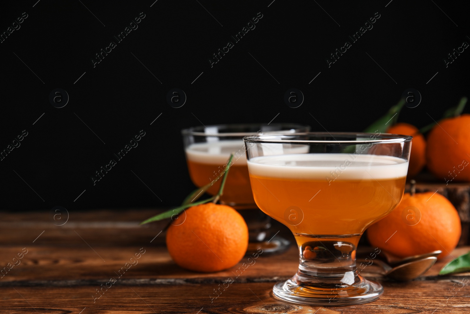 Photo of Delicious tangerine jelly in glass bowl on wooden table. Space for text