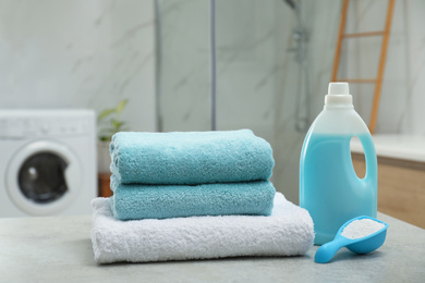 Photo of Clean towels and detergents on table in laundry room