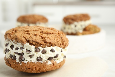 Photo of Sweet delicious ice cream cookie sandwich with chocolate chips on table, closeup. Space for text