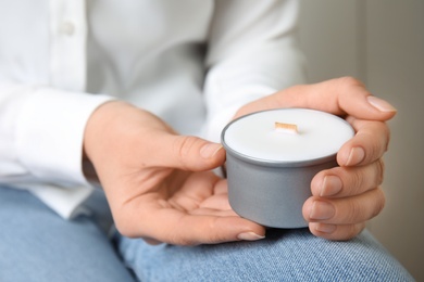 Photo of Woman holding candle with wooden wick on grey background, closeup