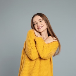 Photo of Beautiful young woman in yellow sweater on grey background. Winter season