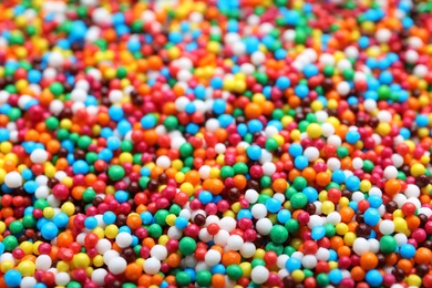 Bright colorful sprinkles as background, closeup. Confectionery decor