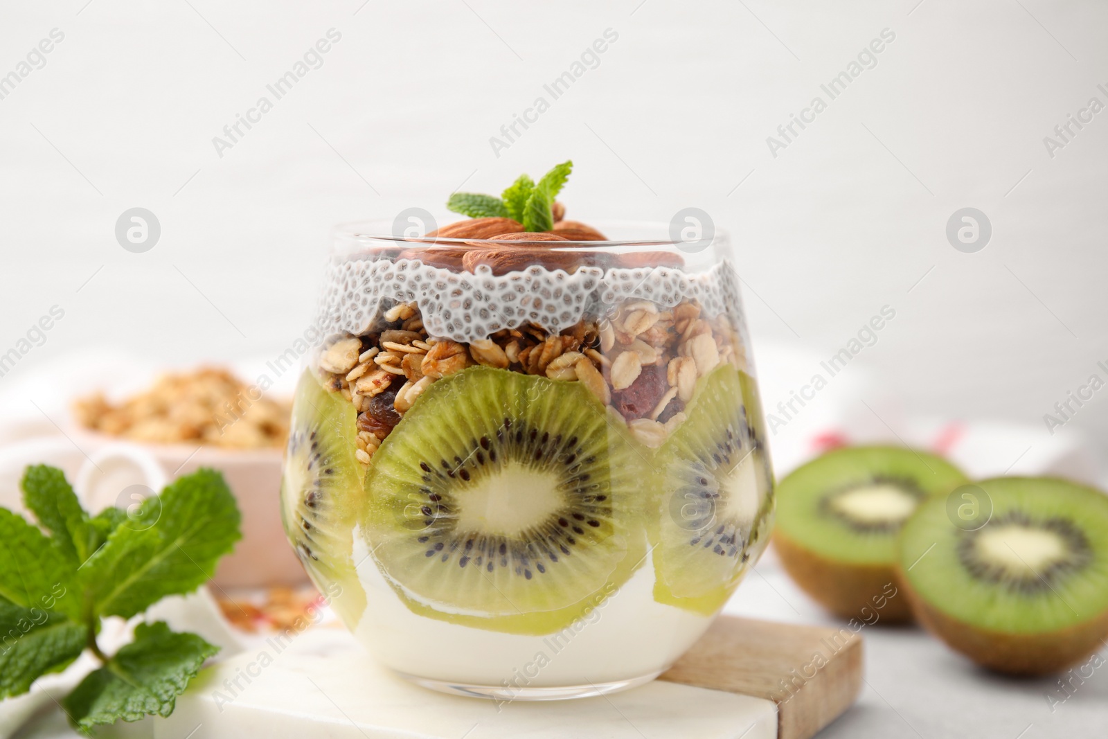 Photo of Delicious dessert with kiwi, chia seeds and almonds on light table, closeup