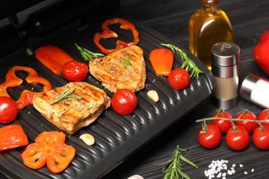 Photo of Electric grill with different products on black wooden table